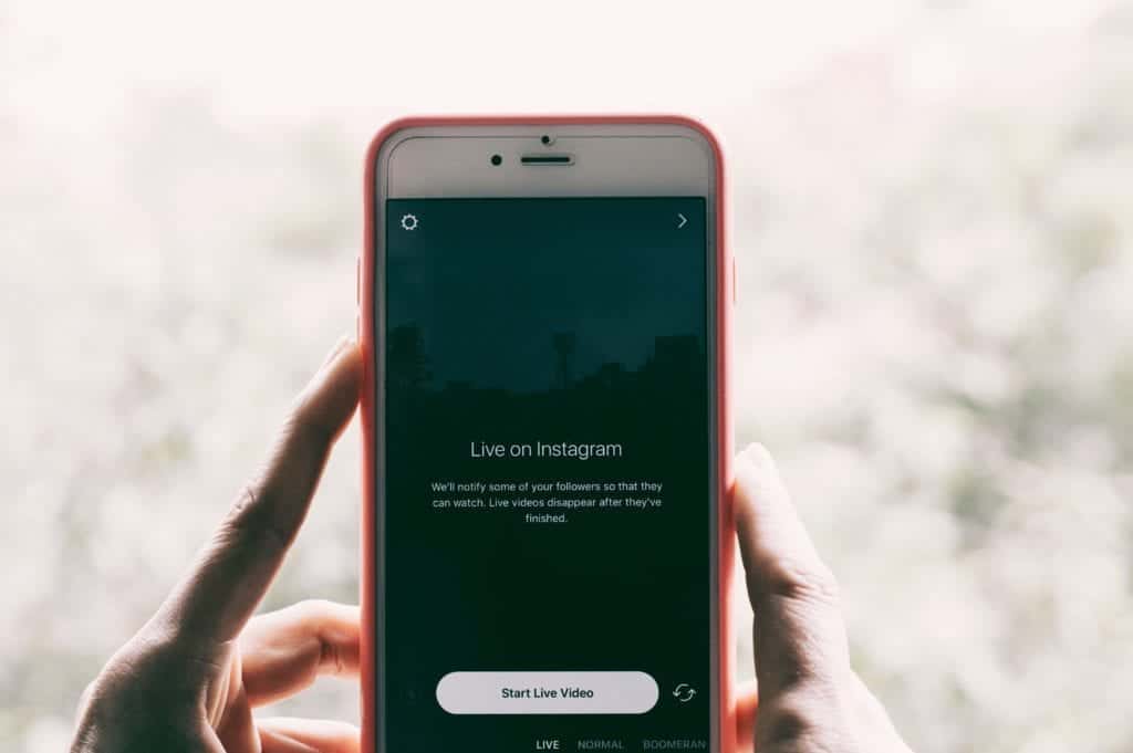 Hand holding phone with words 'live on instagram' and 'start live video'